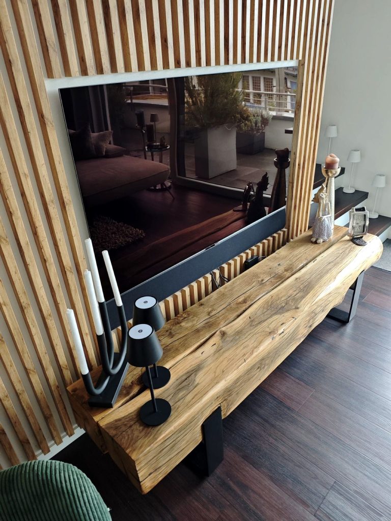Lowboard aus Eichenbalken mit Kerzen vor einer Wand mit Holzlamellen